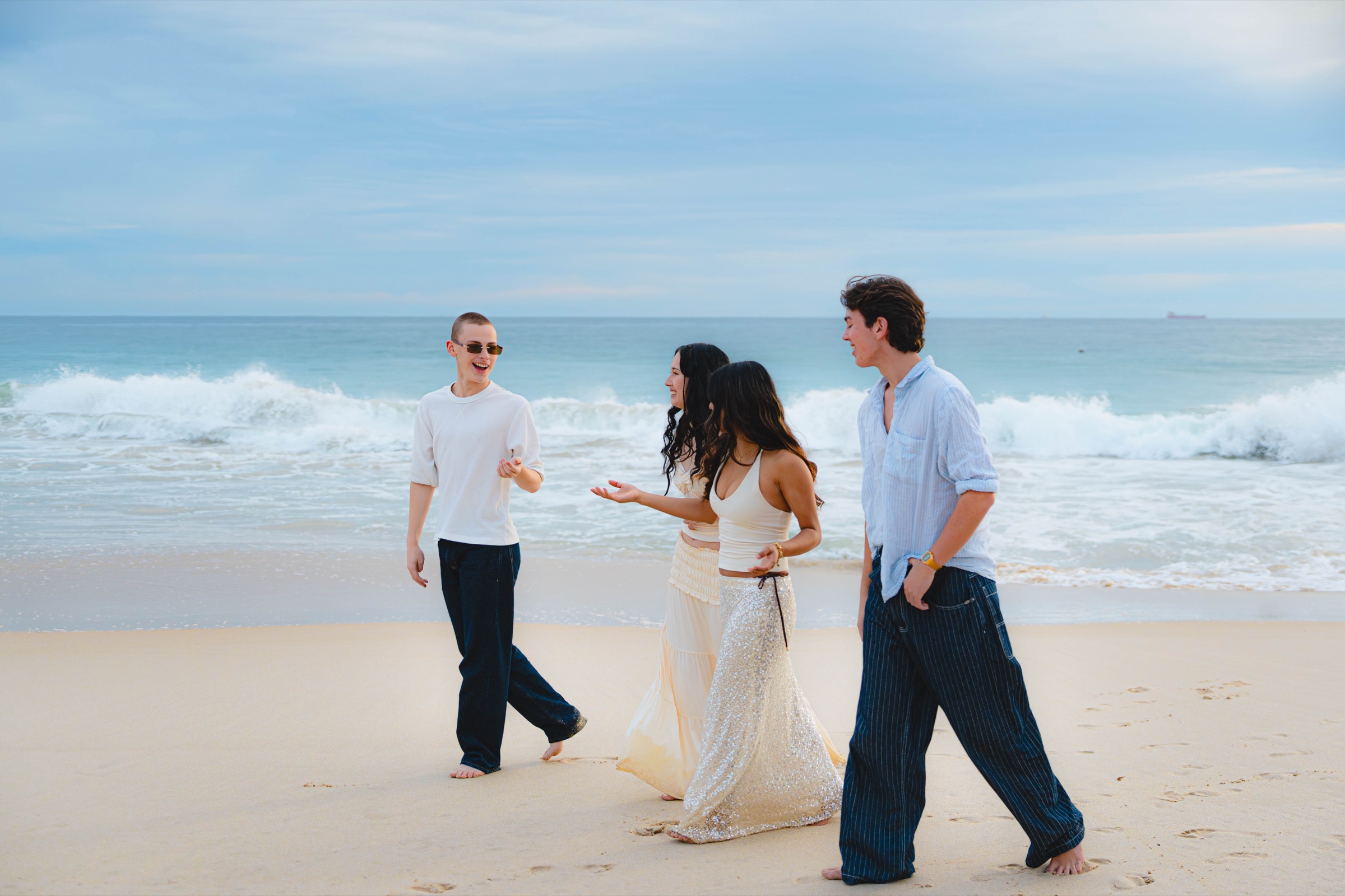 Four friends walking and laughing on a bright beach