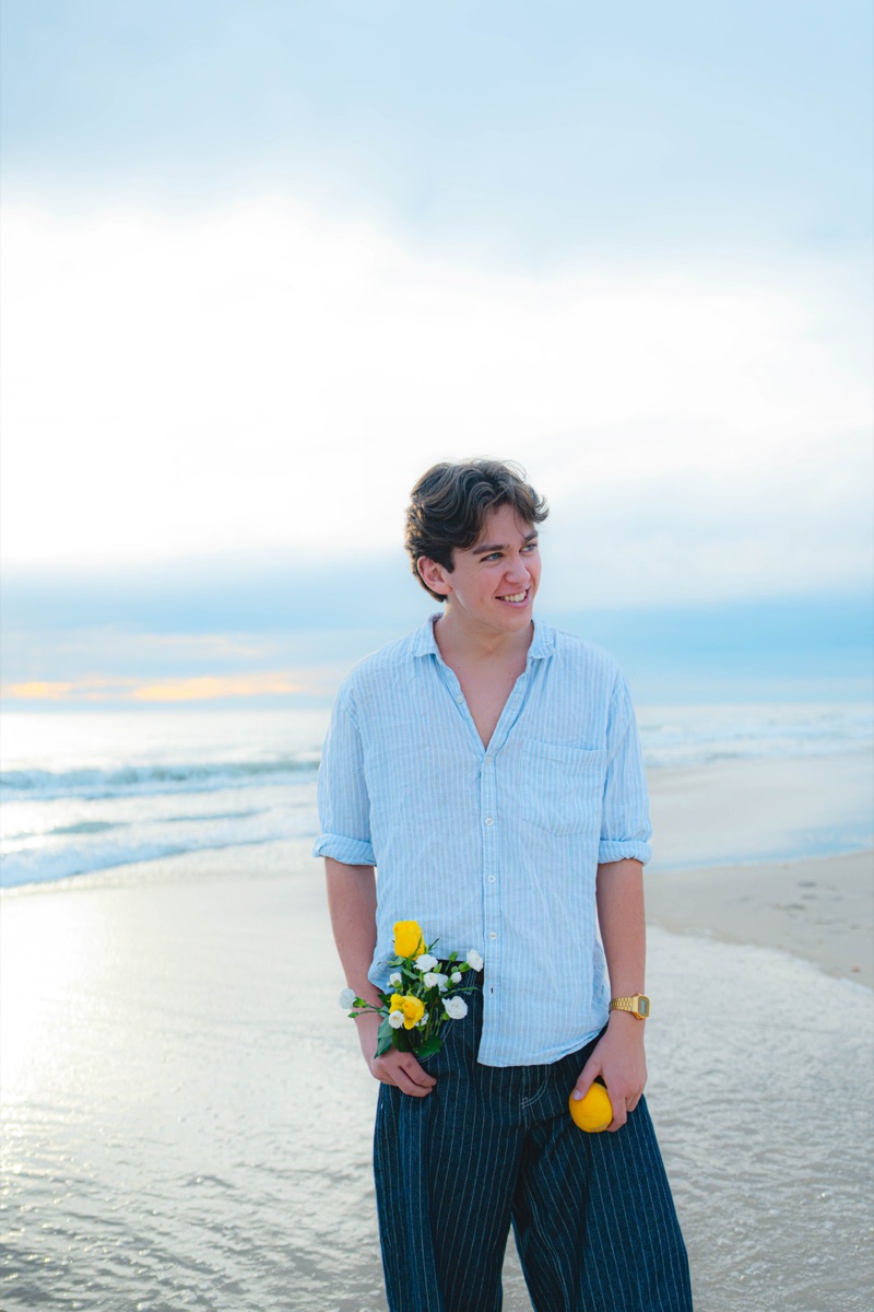 Man holding yellow roses and a lemon at the beach
