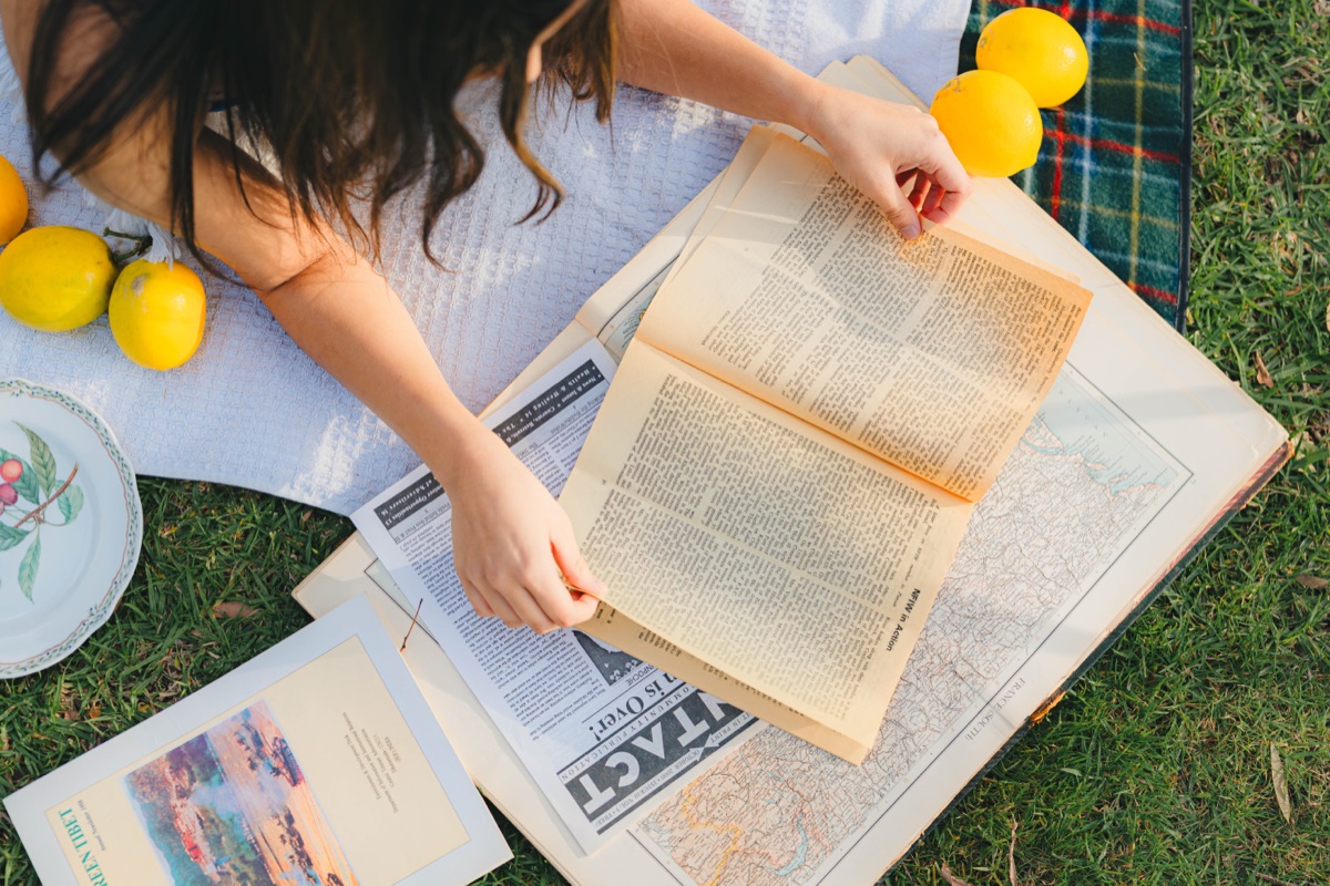 Open book and map spread over a picnic blanket with lemons
