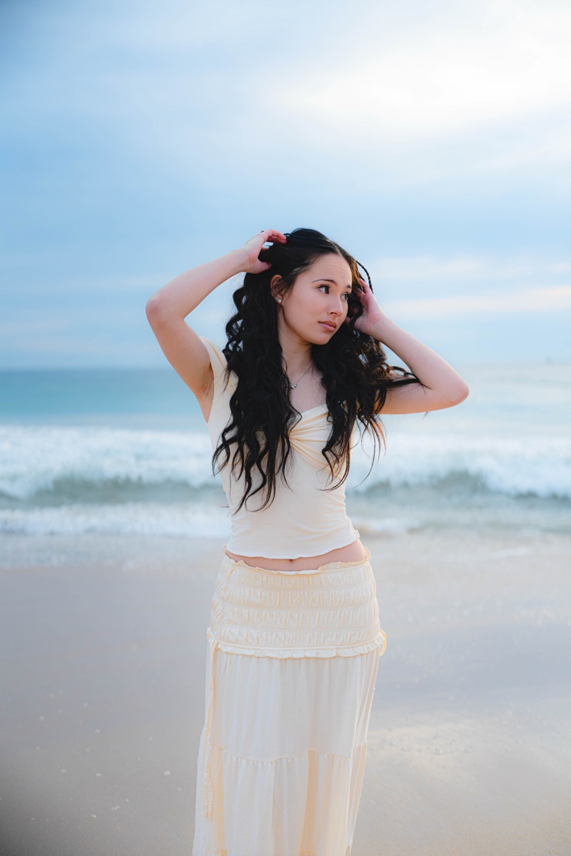 Woman in cream standing against soft ocean light