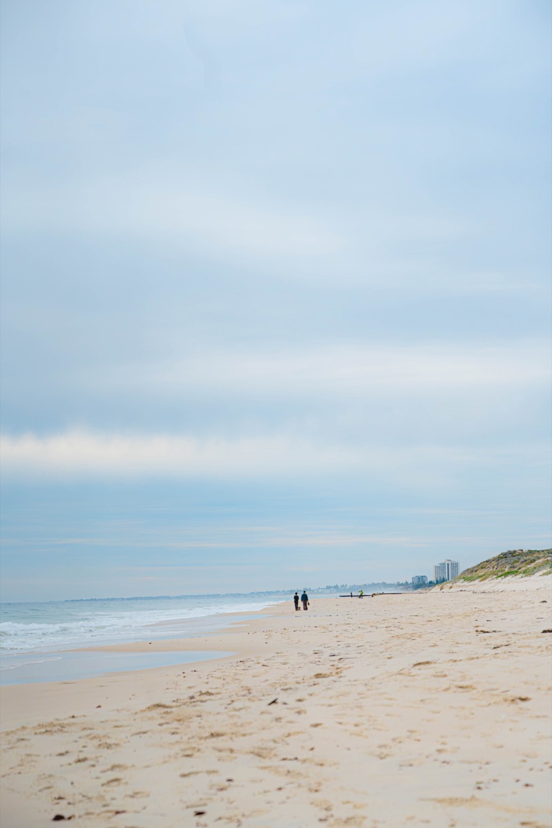 Wide beach view with dunes and a soft blue sky