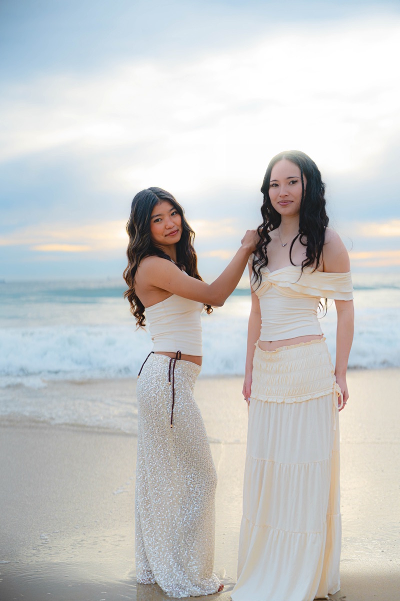 Two women posing on the shoreline in cream outfits