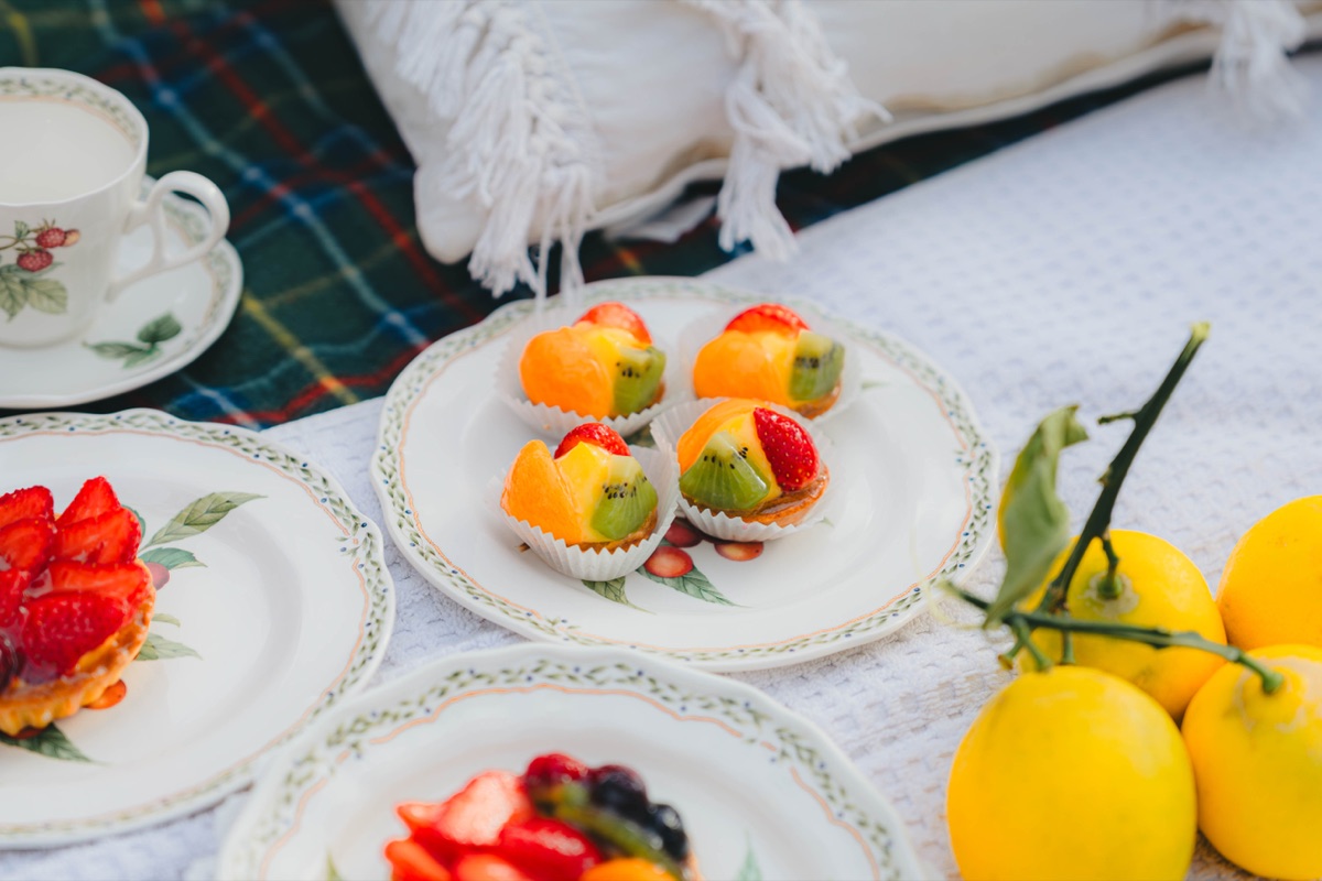 Fruit tarts, lemons, and patterned plates on a picnic blanket